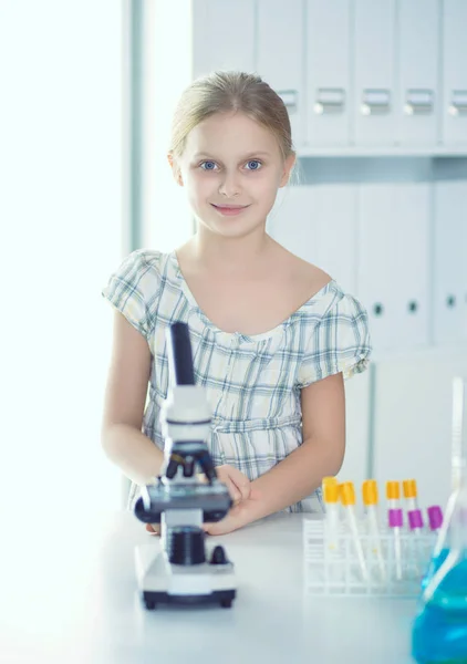 Colegiala mirando a través del microscopio en la clase de ciencias — Foto de Stock