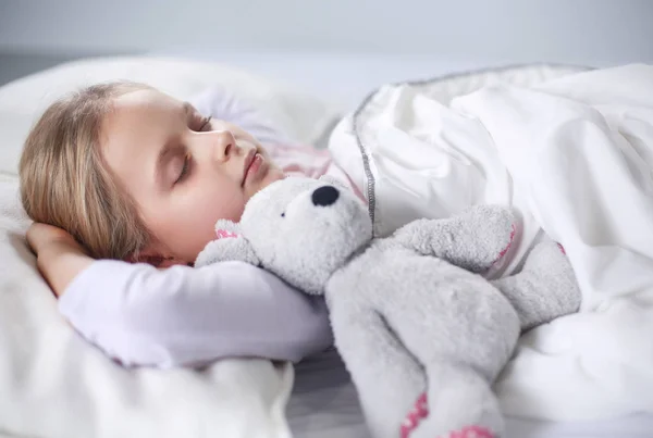 Kleines Mädchen schläft im Bett mit einem Spielzeug-Teddybär — Stockfoto