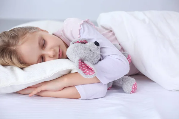 Kleines Mädchen schläft im Bett mit einem Spielzeug-Teddybär — Stockfoto