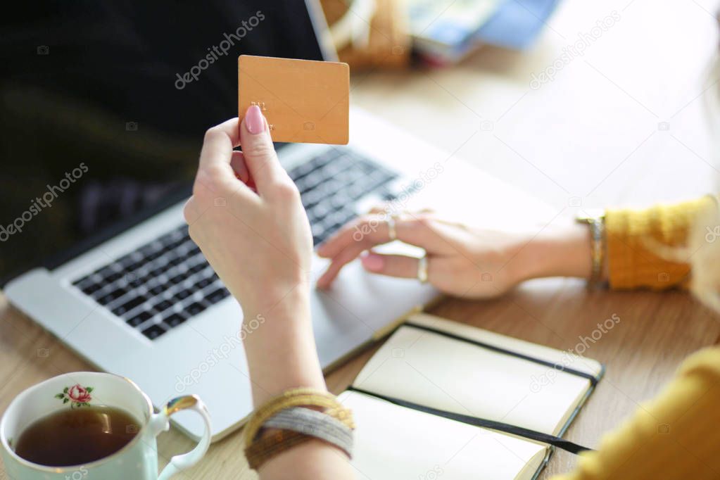 Young woman holding credit card and using laptop computer. Online shopping concept