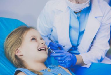 Küçük kız dişçi ofisinde oturuyor.