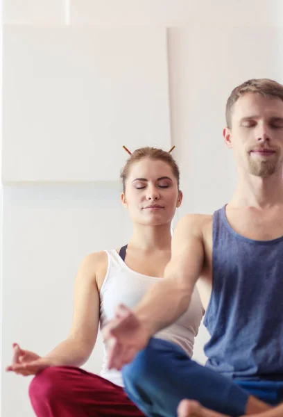 Young healthy couple in yoga position on white background