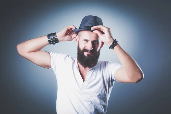 Portrait of handsome bearded man in hat standing , isolated on grey background — Stock Photo, Image