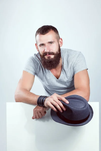 Portrait of young man in hat standing near blank, isolated on white background — Stock Photo, Image