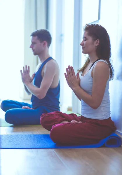 Joven pareja sana en posición de yoga sobre fondo blanco — Foto de Stock