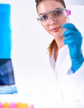 Kadın araştırmacı, beyaz arka planda izole edilmiş ilaç şişeleri ve mataralarla çevrili.