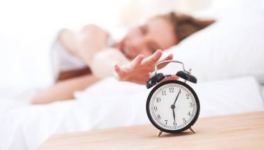 Evdeki yatak odasında uyuyan genç kadın ve çalar saat.