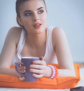 yastık ile beyaz bir yerde yatarken gülümseyen genç kadın