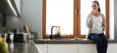 Mutfakta dijital tablet kullanan güzel genç bir kadın.