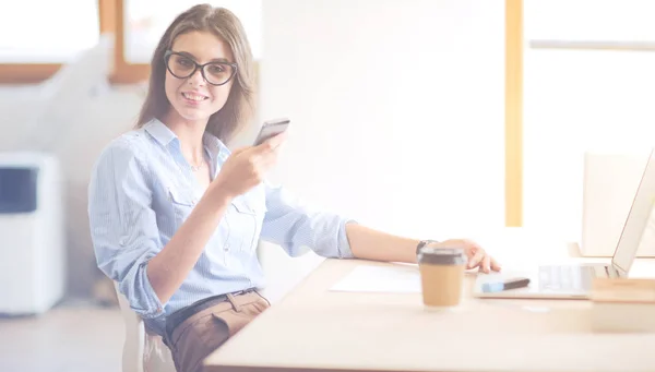 Vacker ung affärskvinna sitter vid skrivbordet och pratar på mobiltelefon — Stockfoto