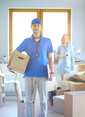 Mavi üniformalı gülümseyen kurye servis konseptine paket kutusu teslim eden teslimatçı. Mavi üniformalı gülümseyen teslimatçı.