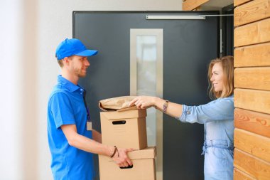Mavi üniformalı gülümseyen kurye servis konseptine paket kutusu teslim eden teslimatçı. Mavi üniformalı gülümseyen teslimatçı.
