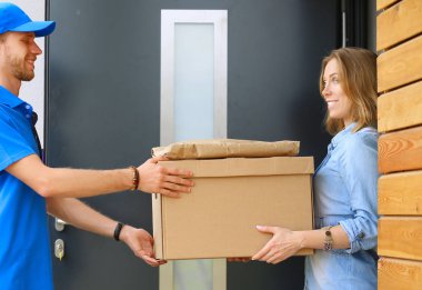 Mavi üniformalı gülümseyen kurye servis konseptine paket kutusu teslim eden teslimatçı. Mavi üniformalı gülümseyen teslimatçı.