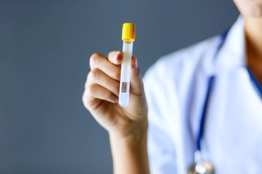 Laboratuvarda ya da laboratuvarda test tüpüne bakarak kadın tıbbi ya da araştırma uzmanı ya da doktor.