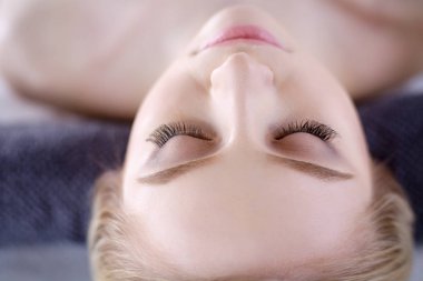 Masaj masasında uzanmış gözleri kapalı rahatlayan genç bir kadın. - Kadın. Spa salonu