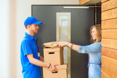 Mavi üniformalı gülümseyen kurye servis konseptine paket kutusu teslim eden teslimatçı. Mavi üniformalı gülümseyen teslimatçı.