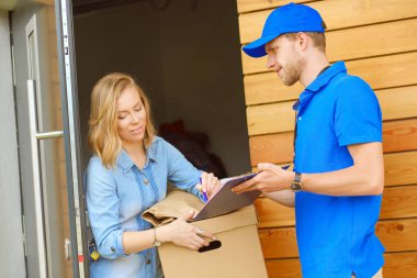 Mavi üniformalı gülümseyen kurye servis konseptine paket kutusu teslim eden teslimatçı. Mavi üniformalı gülümseyen teslimatçı.