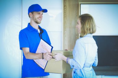 Mavi üniformalı gülümseyen kurye servis konseptine paket kutusu teslim eden teslimatçı. Mavi üniformalı gülümseyen teslimatçı.