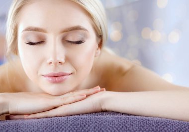 Masaj masasında uzanmış gözleri kapalı rahatlayan genç bir kadın. - Kadın. Spa salonu