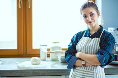 Mutfakta sobanın yanında duran genç bir kadın. .
