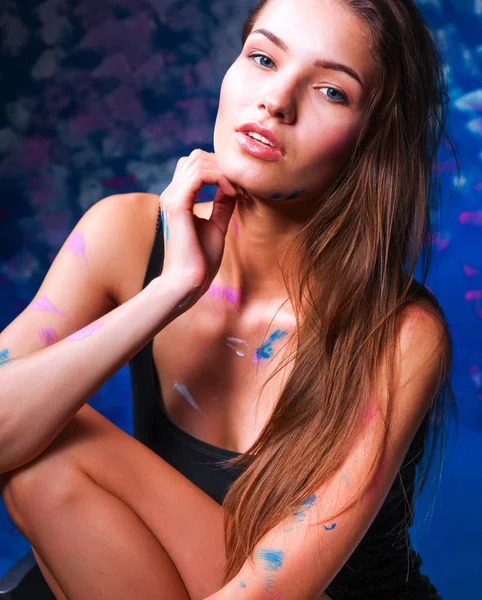 Young beautiful woman sitting near painting wall — Stock Photo, Image