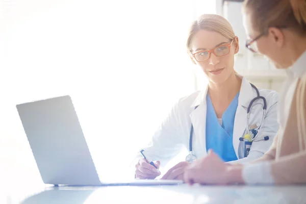 Doctor y pareja de pacientes están discutiendo algo, sentados en el escritorio. — Foto de Stock