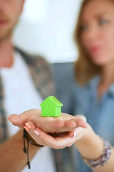 Modelo de casa en la mano de una pareja, de pie en un nuevo hogar. Casa modelo . —  Fotos de Stock