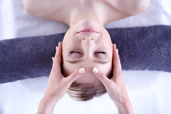 Mujer joven acostada en una mesa de masaje, relajándose con los ojos cerrados. Una mujer. Salón de spa — Foto de Stock