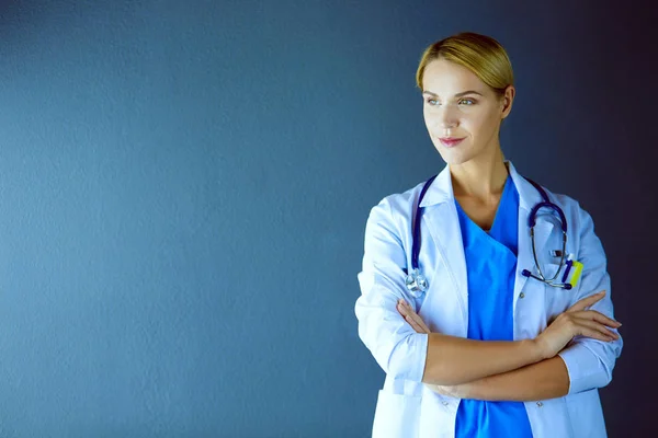 Retrato de una joven doctora con una bata blanca de pie en el hospital. — Foto de Stock