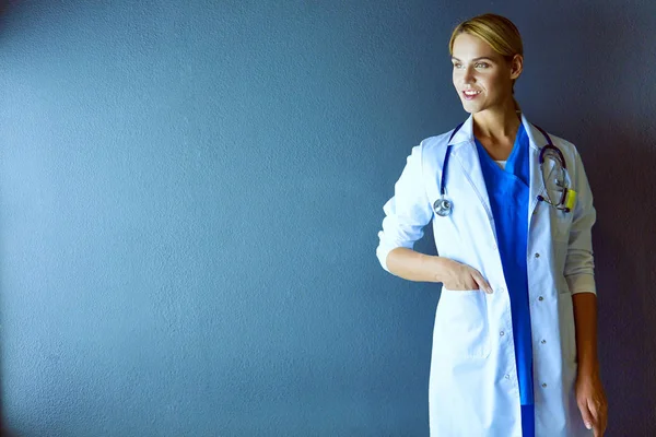 Retrato de una joven doctora con una bata blanca de pie en el hospital. — Foto de Stock