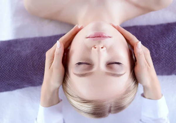 Mujer joven acostada en una mesa de masaje, relajándose con los ojos cerrados. Una mujer. Salón de spa —  Fotos de Stock