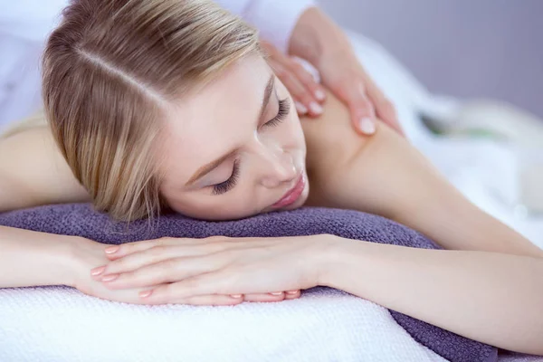 Mujer joven acostada en una mesa de masaje, relajándose con los ojos cerrados. Una mujer. Salón de spa — Foto de Stock