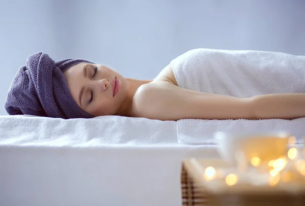 Jonge vrouw liggend op een massagetafel, ontspannend met gesloten ogen. Vrouw. Kuuroord — Stockfoto