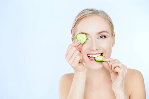 Young beautiful woman with cucumber slices on white background — Stock Photo, Image