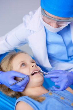 Küçük kız dişçi ofisinde oturuyor.