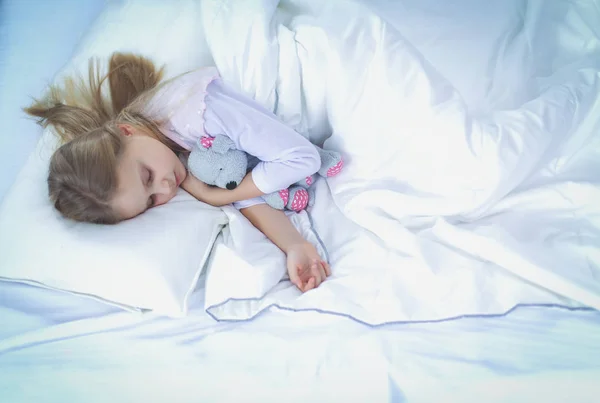 Barn lilla flicka sover i sängen med en leksak nallebjörn — Stockfoto