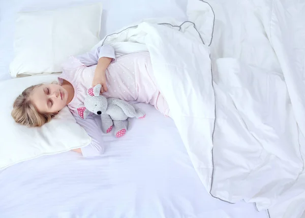 Child little girl sleeps in the bed with a toy teddy bear — Stock Photo, Image