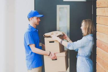 Mavi üniformalı gülümseyen kurye servis konseptine paket kutusu teslim eden teslimatçı. Mavi üniformalı gülümseyen teslimatçı.