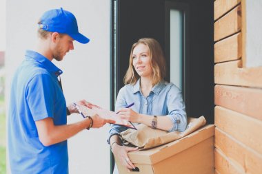 Mavi üniformalı gülümseyen kurye servis konseptine paket kutusu teslim eden teslimatçı. Mavi üniformalı gülümseyen teslimatçı.