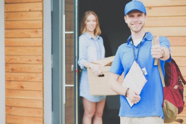 Mavi üniformalı gülümseyen kurye servis konseptine paket kutusu teslim eden teslimatçı. Mavi üniformalı gülümseyen teslimatçı.