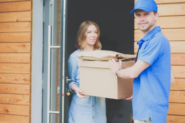 Mavi üniformalı gülümseyen kurye servis konseptine paket kutusu teslim eden teslimatçı. Mavi üniformalı gülümseyen teslimatçı.