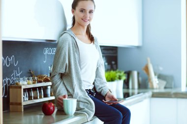 modern mutfakta otururken cep telefonu kullanan kadın.