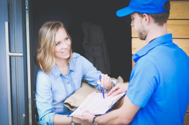 Mavi üniformalı gülümseyen kurye servis konseptine paket kutusu teslim eden teslimatçı.