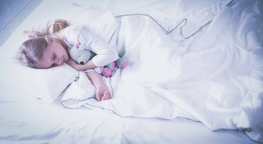 çocuk oyuncak oyuncak ayı ile yatakta uyur küçük kız