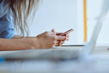 Dizüstü bilgisayar ekranına bakarak office tablosunda oturan genç kadın