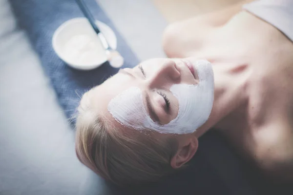 Mascarilla facial. Hermosa joven en el spa, mujer cosmética aplicando mascarilla facial — Foto de Stock