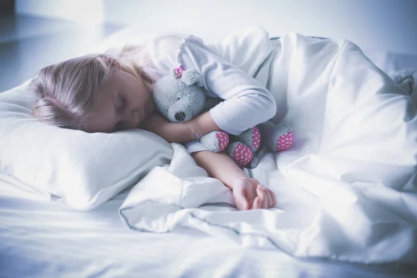 Niño niña duerme en la cama con un osito de peluche de juguete — Foto de Stock