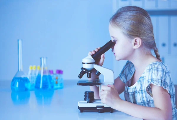 Colegiala mirando a través del microscopio en la clase de ciencias — Foto de Stock