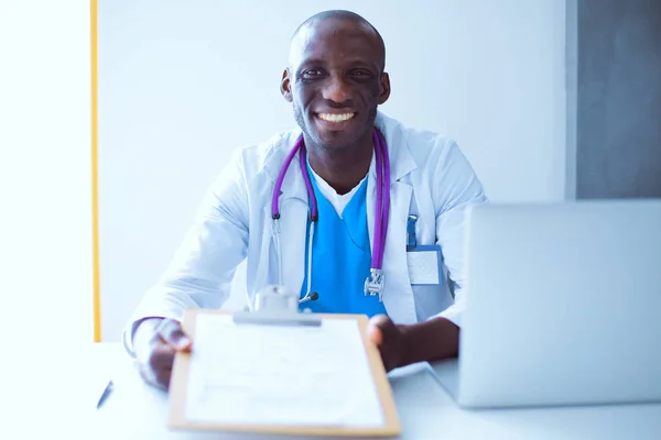 Молодий африканський лікар працює на ноутбуці за столом — стокове фото