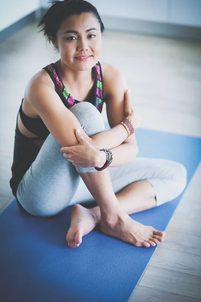 Retrato de una mujer sonriente de yoga sentada en la esterilla de yoga después del entrenamiento en el estudio de yoga — Foto de Stock